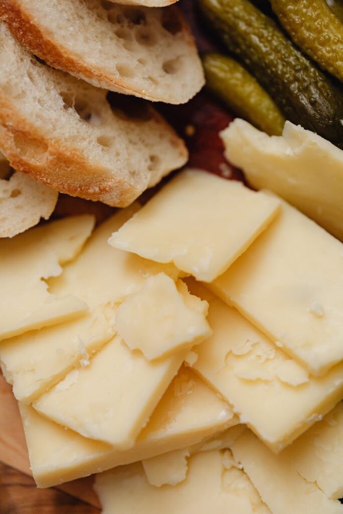 pexels-photo-6660052 Delicious assortment featuring sliced cheese, rustic bread, and pickles, perfect for gourmet presentation.